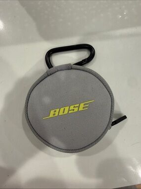 Bose Light Gray Round Earbud Case with Yellow Logo and Black Carabiner